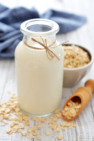 Oat milk in bottle on white wooden background. の写真素材