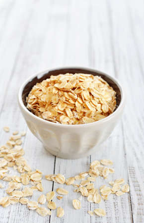 Oat flakes in bowl on white wooden backgroundの写真素材