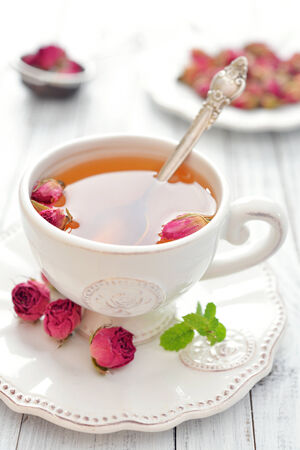 Tea rose flowers  and cup of tea on wooden backgroundの写真素材