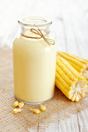 Fresh sweet corn juice (corn milk) in bottle on wooden backgroundの写真素材