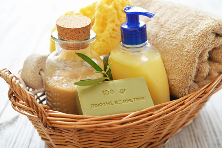 Shower gel with olive soap and bath towels in basket on wooden backgroundの写真素材