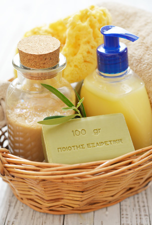 Shower gel with olive soap and bath towels in basket on wooden backgroundの写真素材