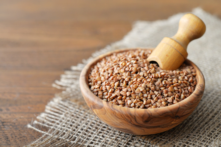 Raw buckwheat seeds in bowl on wooden backgroundの写真素材
