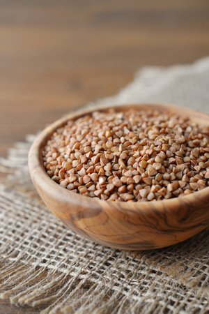 Raw buckwheat seeds in bowl on wooden backgroundの写真素材