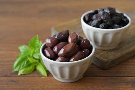 Olives in bowls with fresh basil on wooden backgroundの写真素材