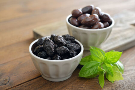 Olives in bowls with fresh basil on wooden backgroundの写真素材