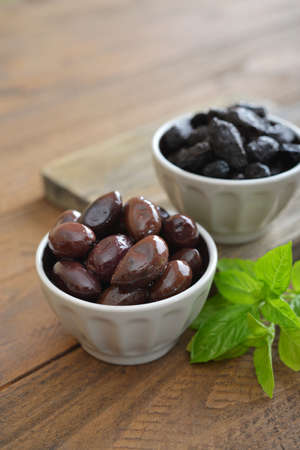Olives in bowls with fresh basil on wooden backgroundの写真素材