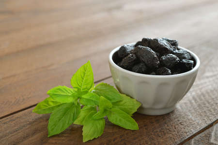Olives with fresh basil on wooden backgroundの写真素材
