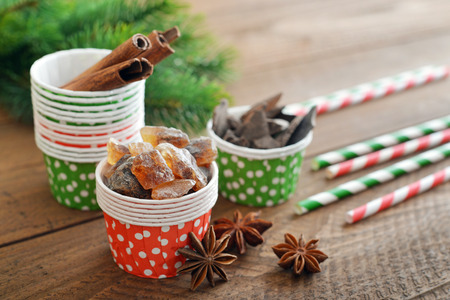 Sugar, cinnamon sticks and chocolate in cupcake cases on wooden backgroundの写真素材