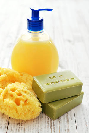 Greek olive soap with shower gel and bath sponge on wooden background. The words on soap translates as best qualityの写真素材