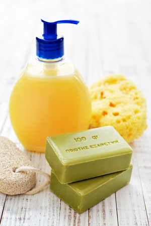 Greek olive soap with shower gel and bath sponge on wooden background. The words on soap translates as best qualityの写真素材