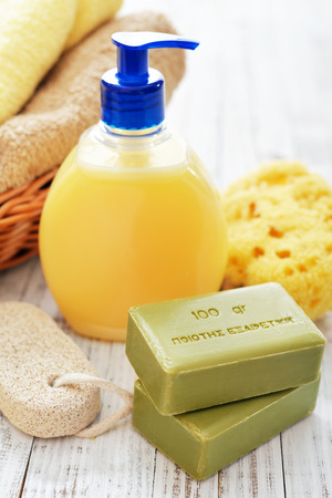 Greek olive soap with shower gel and bath towels on wooden background. The words on soap translates as best qualityの写真素材
