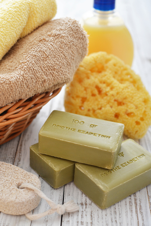 Greek olive soap with shower gel and bath towels on wooden backgroundの写真素材