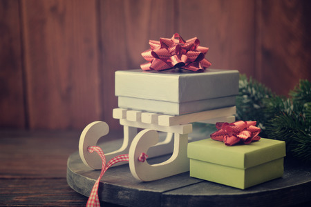 Gift boxes and sled with fir tree branches on wooden backgroundの写真素材