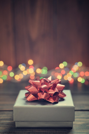 Silver gift box with red bow over wooden backgroundの写真素材