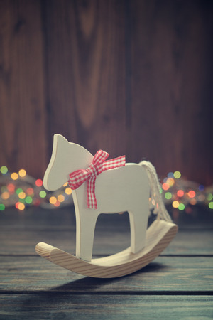 Toy horse with christmas lights on wooden backgroundの写真素材