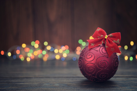 Red christmas decorative ball with christmas lights on wooden backgroundの写真素材