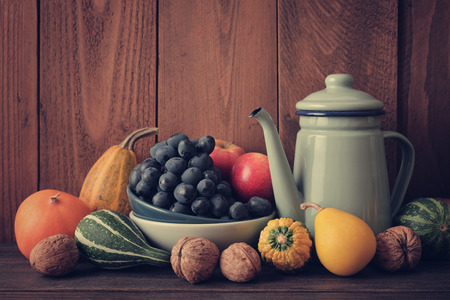 Fresh pumpkins with fruits and vintage kettle on wooden backgroundの写真素材