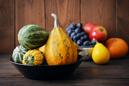 Fresh pumpkins with fruits on wooden backgroundの写真素材