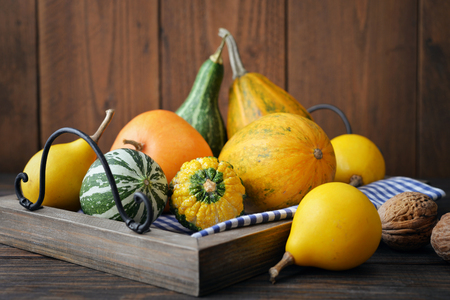Decorative pumpkins with nuts on tray over wooden backgroundの写真素材