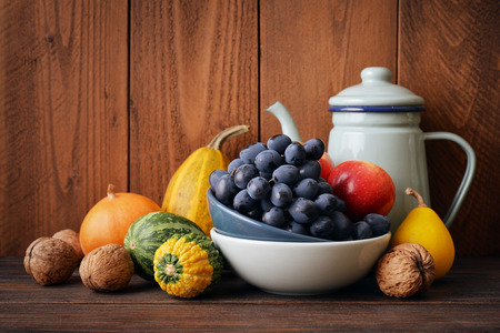 Fresh pumpkins with fruits and vintage kettle on wooden backgroundの写真素材
