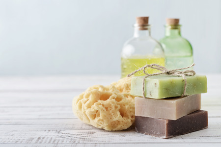 Stack of soap bars with sponge and bottles on light backgroundの写真素材