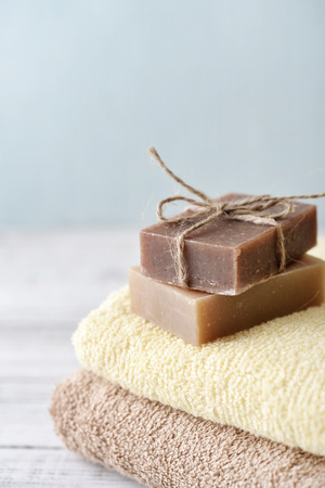 Stack of bath towels with soap bars on light wooden background closeupの写真素材