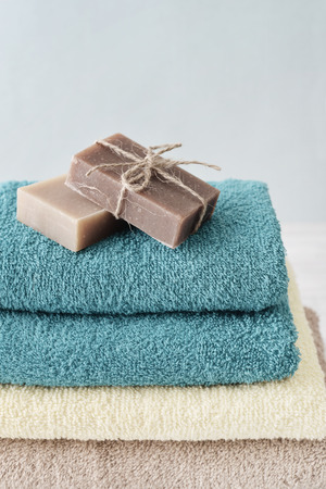 Stack of bath towels with soap bars on light wooden background closeupの写真素材