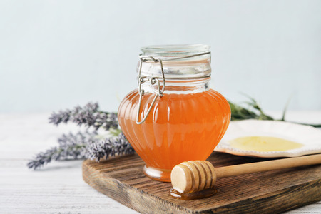Honey in jar with honey dipper on vintage wooden backgroundの写真素材