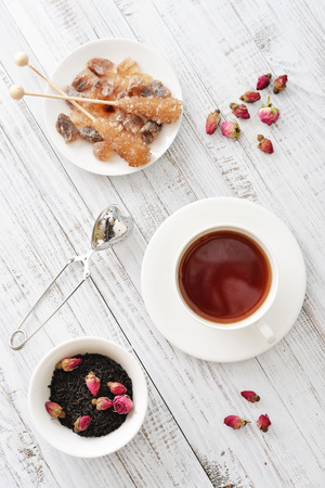Cup of tea with dry rose buds and tea strainer in the shape of heartの写真素材