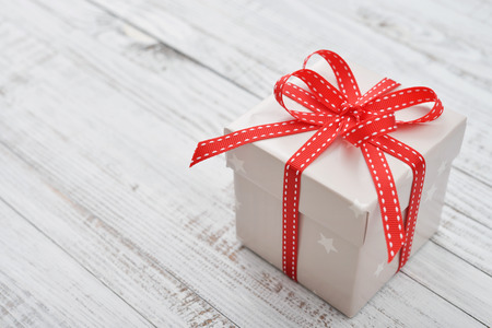 Christmas present wrapped in decorative wrapping paper with red ribbon closeupの写真素材