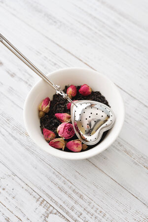 Tea strainer in the shape of heart with dry rose budsの写真素材
