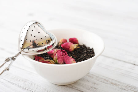 Tea strainer in the shape of heart with dry rose budsの写真素材