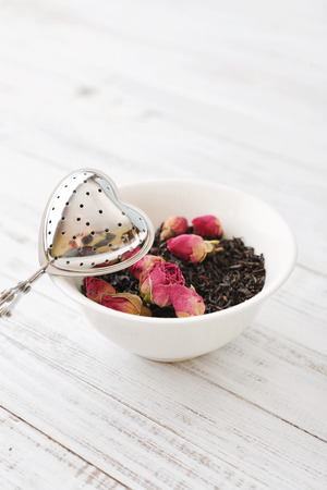 Tea strainer in the shape of heart with dry rose budsの写真素材