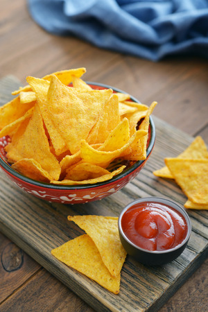 Corn nachos in bowl with sauce on wooden backgroundの写真素材