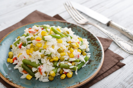Vegetable risotto on plate with fork and knife on wooden backgroundの写真素材