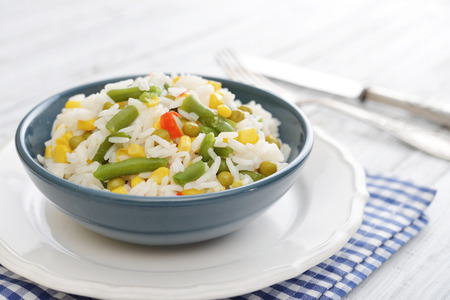Vegetable risotto on plate with fork and knife on wooden backgroundの写真素材
