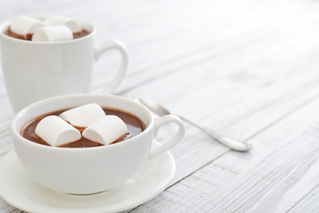 Mug with hot chocolate and marshmallows on wooden tableの写真素材