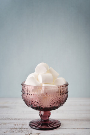 Marshmallows in glass bowl on blue backgroundの写真素材