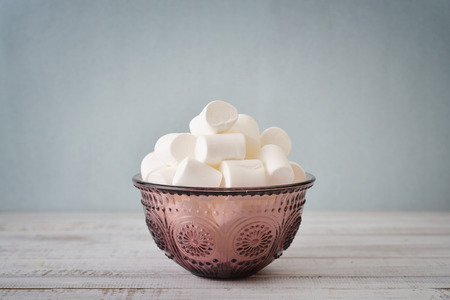 Marshmallows in glass bowl on blue backgroundの写真素材