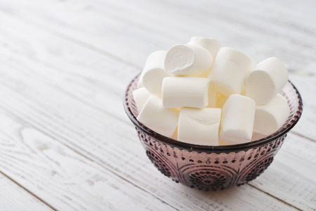 Marshmallows in glass bowl on blue backgroundの写真素材