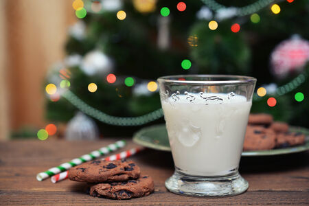 Milk and cookies for Santa Claus with drink straws on wooden backgroundの写真素材