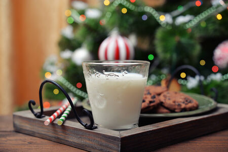 Milk and cookies for Santa Claus with drink straws on wooden trayの写真素材