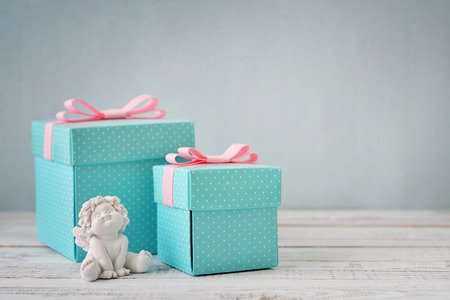 Blue polka dots gift boxes with statuette of angel on wooden backgroundの写真素材
