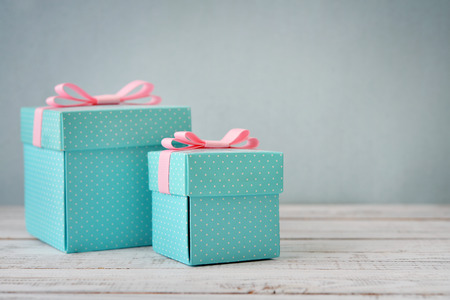Blue polka dots gift boxes with pink ribbons on wooden backgroundの写真素材