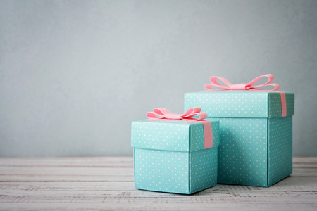 Blue polka dots gift boxes with pink ribbons on wooden backgroundの写真素材