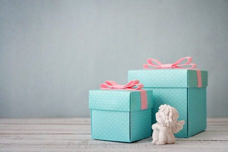 Blue polka dots gift boxes with statuette of angel on wooden backgroundの写真素材