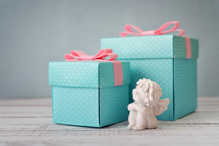 Blue polka dots gift boxes with statuette of angel on wooden backgroundの写真素材