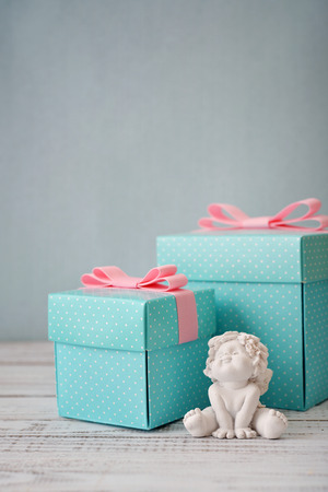 Blue polka dots gift boxes with statuette of angel on wooden backgroundの写真素材