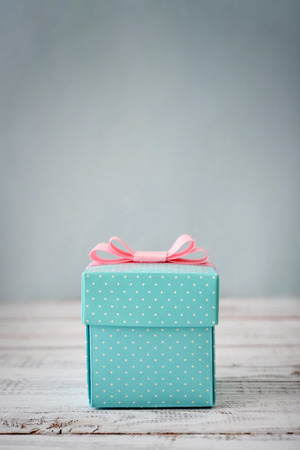 Blue polka dots gift box with pink ribbon on wooden backgroundの写真素材